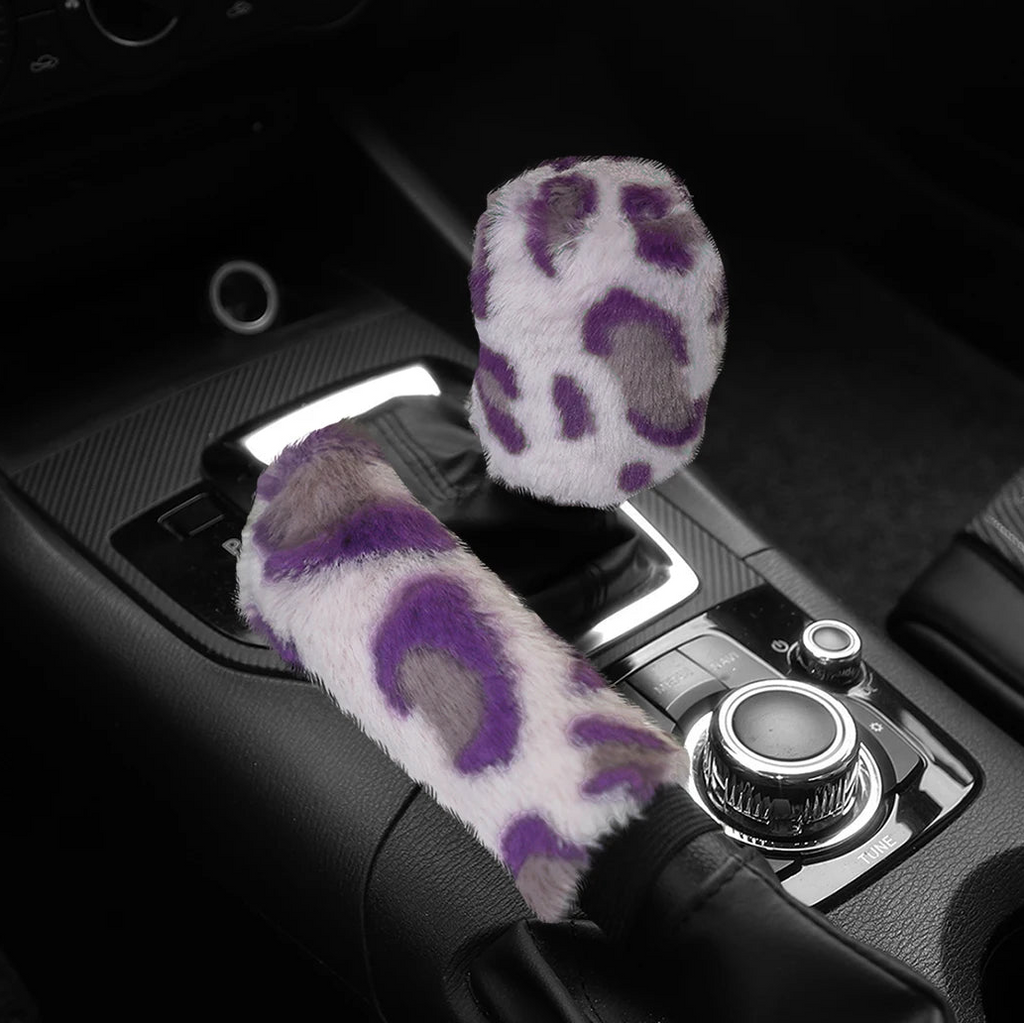 Car handbrake and gear shift cover with paw print design on a black car interior background.